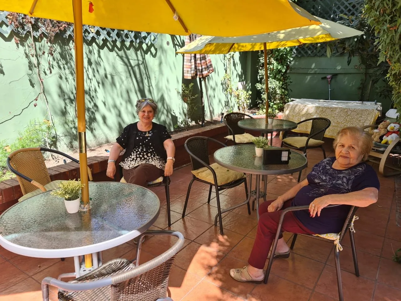 Residentes conversando en la terraza del jardín, bajo el quitasol amarillo
