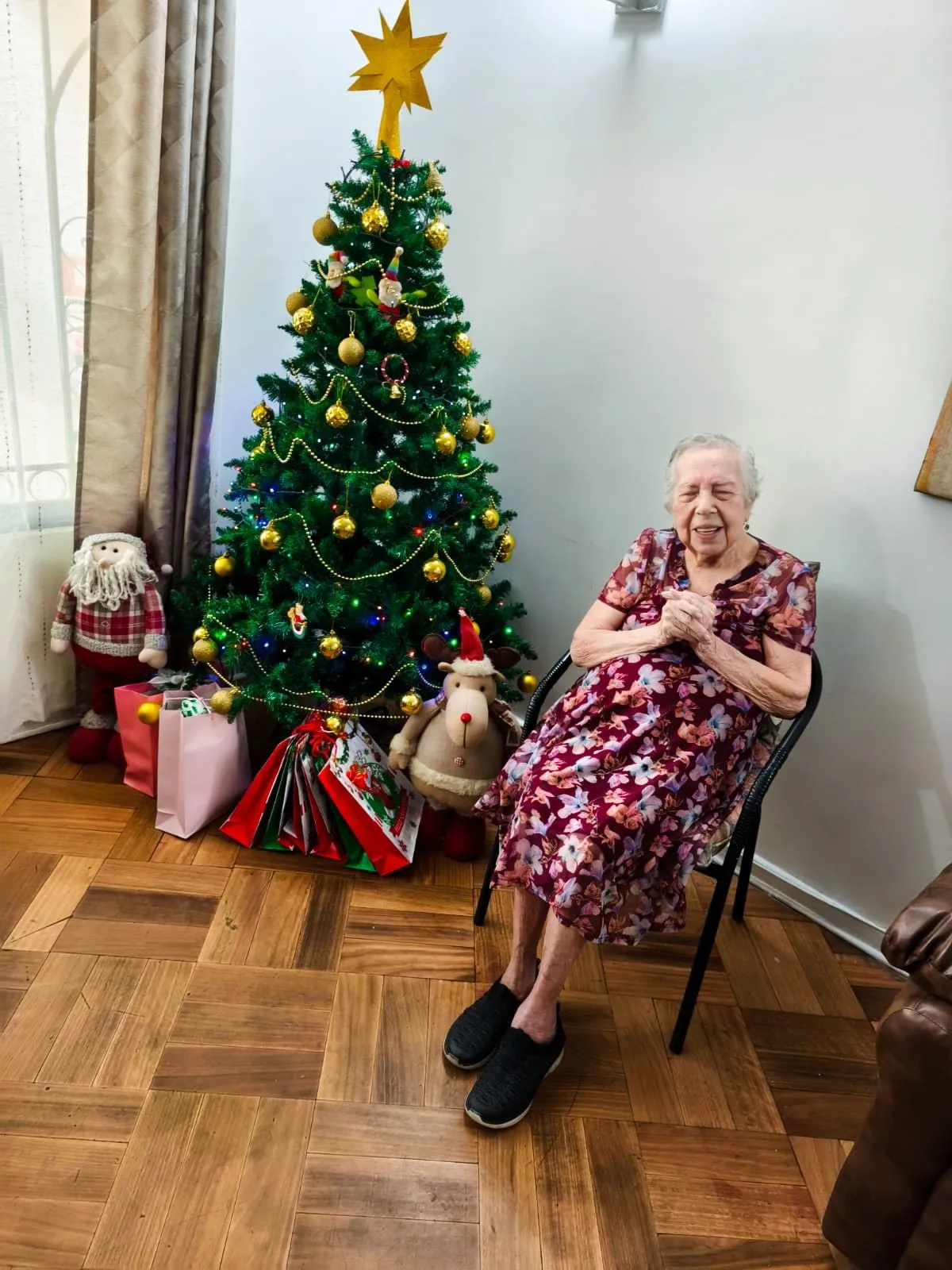 Residente sonriente de pie junto al árbol de Navidad